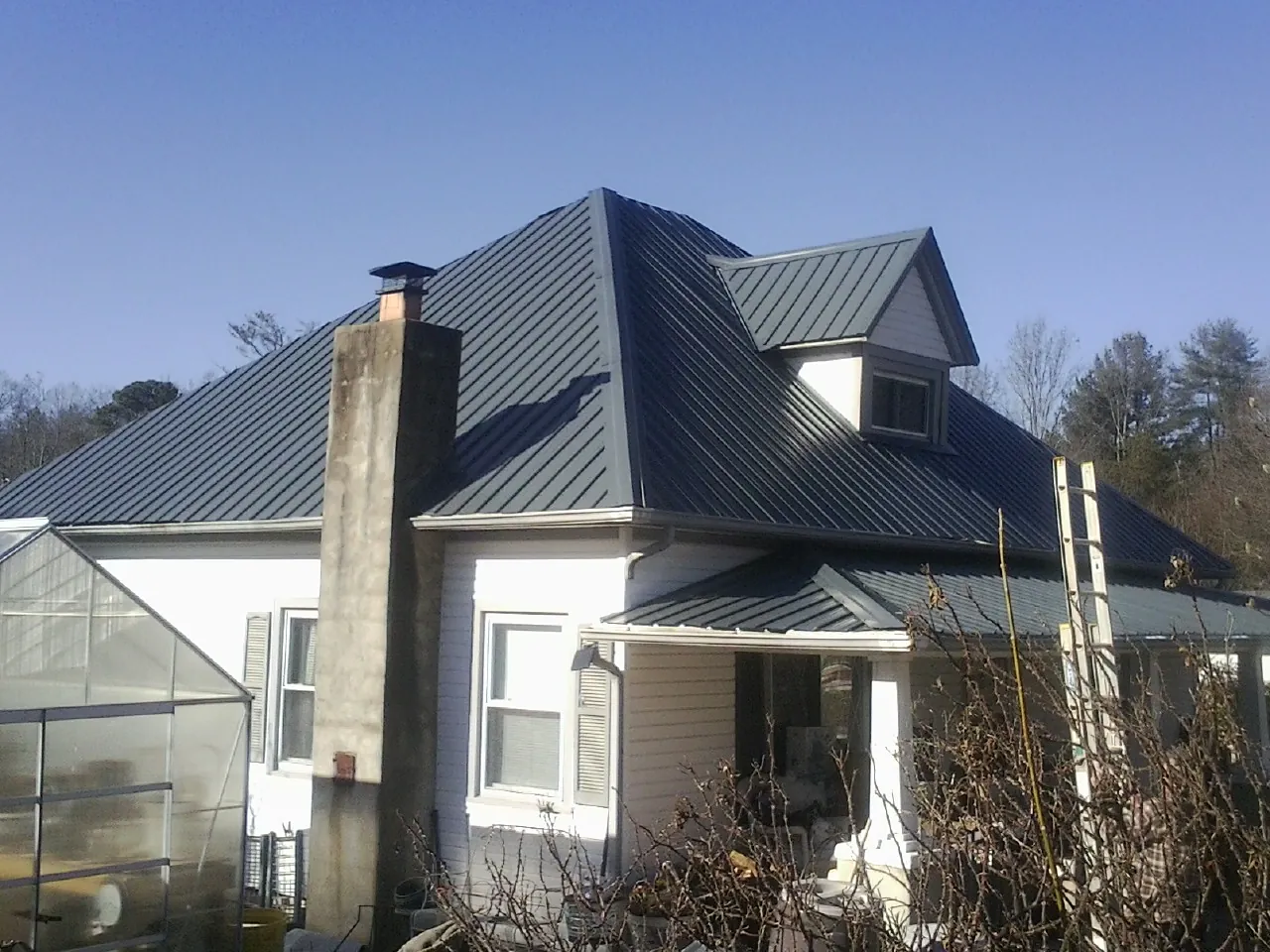 Dark blue standing seam metal roof on a white farmhouse with dormer — Slate & Tile Roof Repair by Roofing Brothers in Ellicott City
