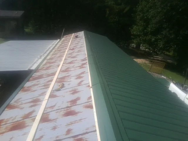 Old rusted panels beside newly installed green metal roofing — Wind Damage Roof Repair by Roofing Brothers in Ellicott City