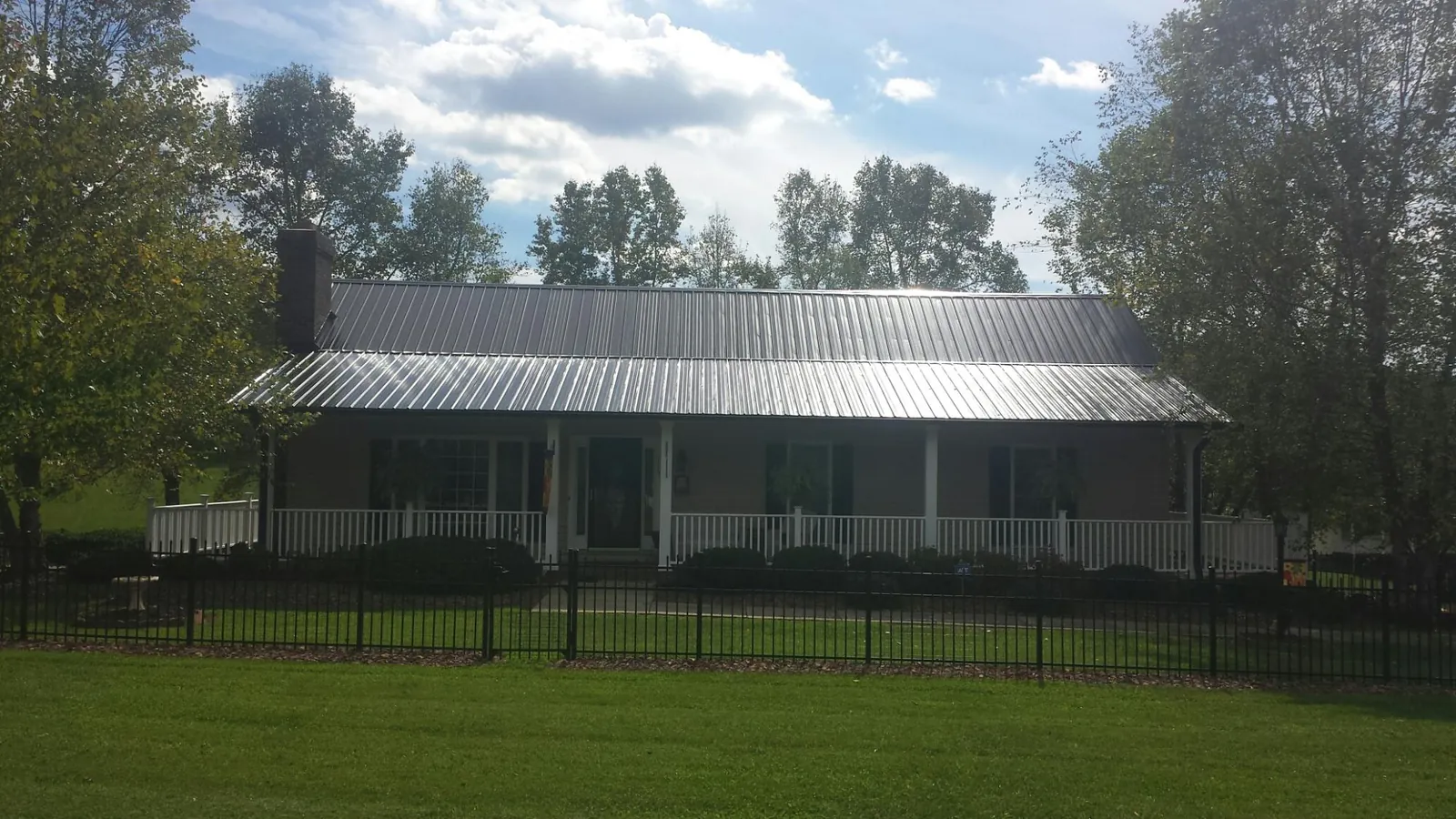 Gray metal roof on a brick ranch with a full width front porch — Gutter Guard Installation work by our crew in Ellicott City