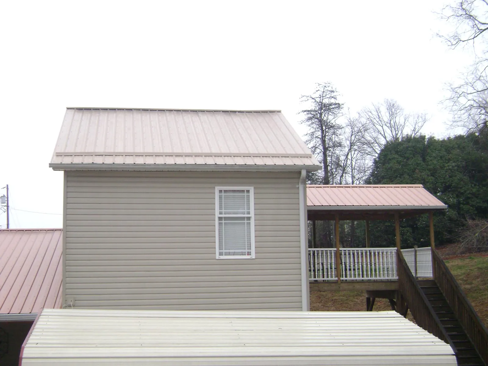 Tan metal roofs on a two story addition and attached porch, from a Roof Replacement job in Ellicott City