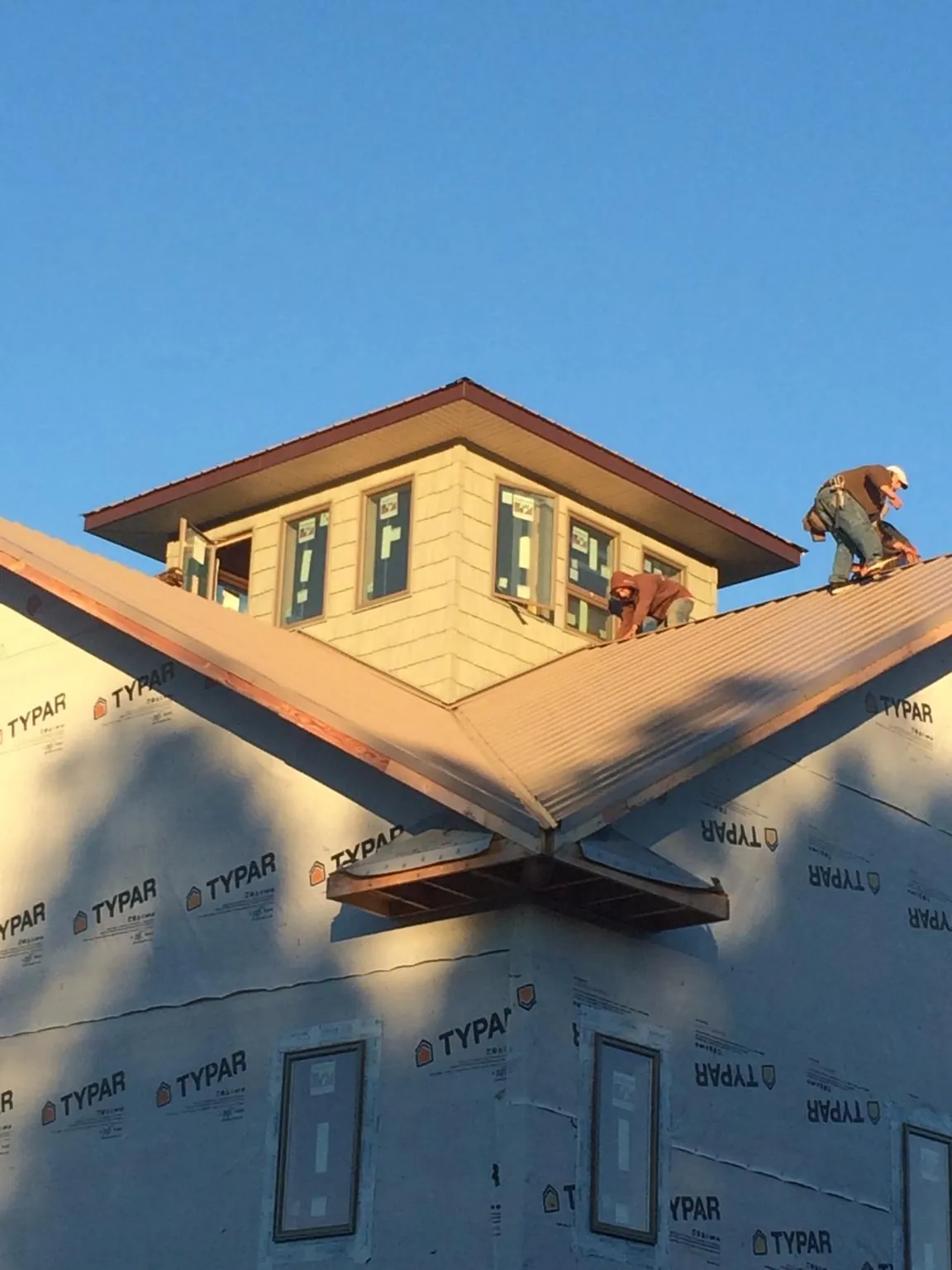 Roofers working around a rooftop cupola on a new metal roof at sunset — Roof Waterproofing in Ellicott City by Roofing Brothers